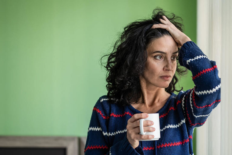 A stressed looking woman holding a coffee mug