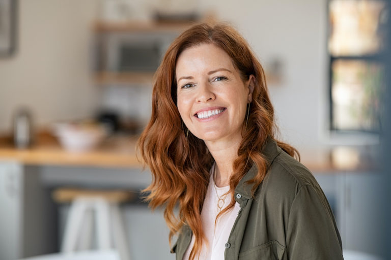 Portrait of a red haired woman who is smiling at the camera