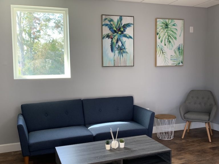 Thrive Dental Associates waiting room with a blue couch, a window, and two palm tree photos on the wall
