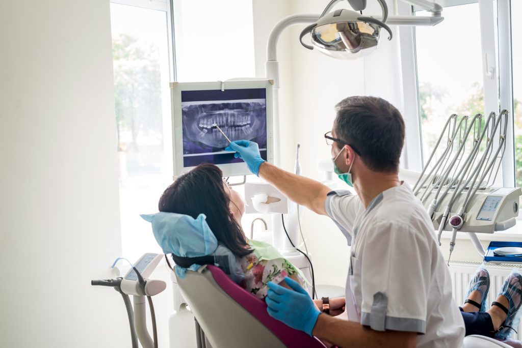 dentist showing patient xray of teeth in dental chair
